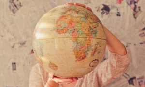 hands carry world map beside newspaper