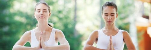 two young women wearing couple t shirt focuses on meditation