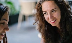 two women happily talk discuss in coffee shop