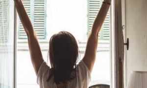 woman facing backward opens window