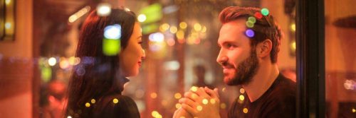 couple holds hands happily smiling looking at each other