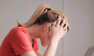 woman scratching head looking at laptop sitting in quiet room