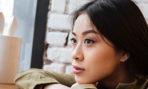 young woman sitting hands on table thinking