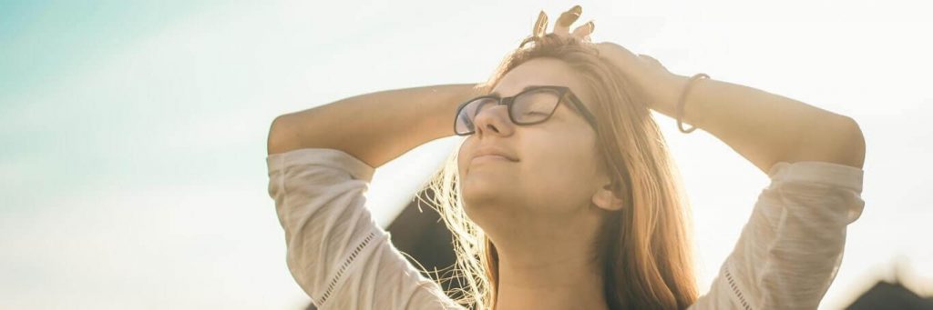 woman stands hand on hair eyes closed gratitude life