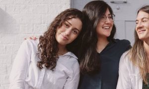 three women standing side by side smiling