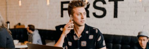 man sits in busy coffee shop answering phone