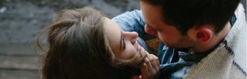 couple stands on bridge looking hugging each other