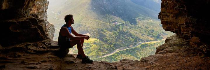man sits on rock looking at beautiful sunny sky breakthrough terrace view