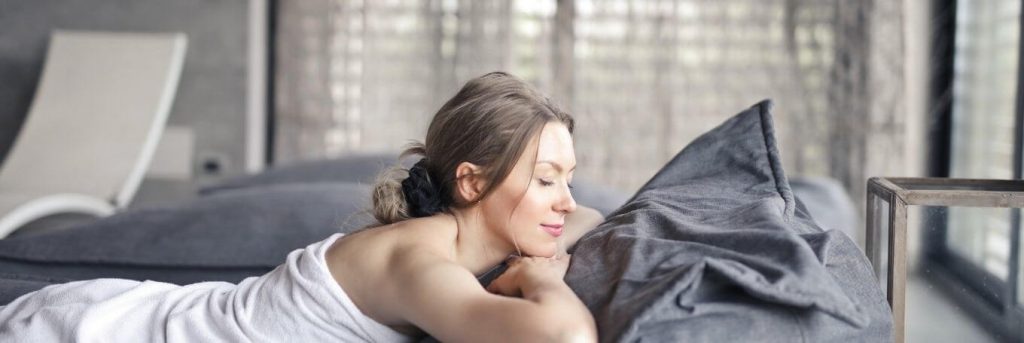 woman eyes closed lies on bed smiling