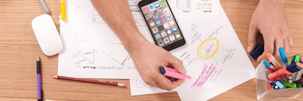 hand using pink highlighter highlighting sentence on paper mindmap table beside iphone pencil case