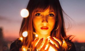 woman holds lights looks serious in dark sky