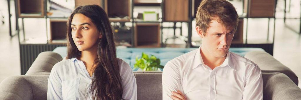 couple has conflict not talking to each other sitting on couch in nicely decorated living room