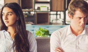 couple has conflict not talking to each other sitting on couch in nicely decorated living room