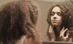 long curly hair girl looks herself in mirror