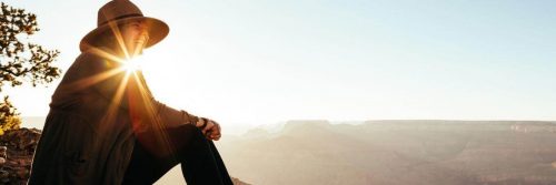 woman sits happily smiling in sunny blue sky