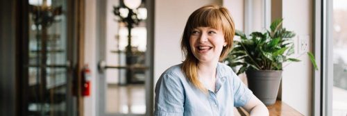 woman sits alone in coffee shop smiling