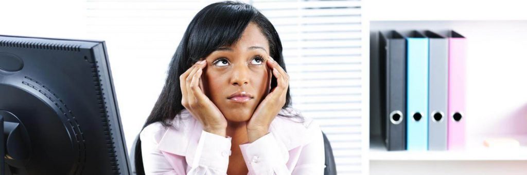 woman sits hand in face confused thinking beside personal computer bookshelf