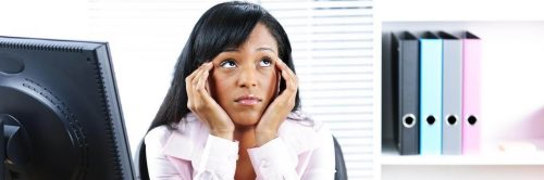 woman sits hand in face confused thinking beside personal computer bookshelf