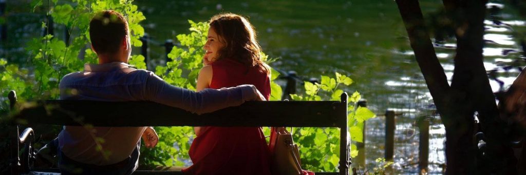 couple sits on bench happily smiling beside lake