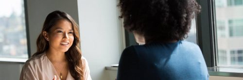 woman happily talks discussed with curly hair woman in office
