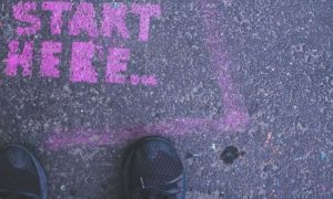 dark shoes stepping on purple sign detailing start here