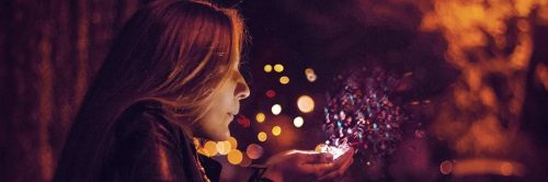woman blowing candles on hands
