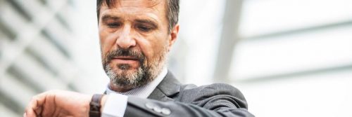 businessman checking watch as of being late