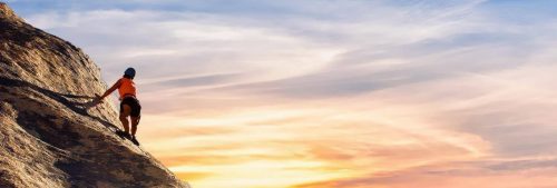 woman climbs mountain in red blue cloudy sky