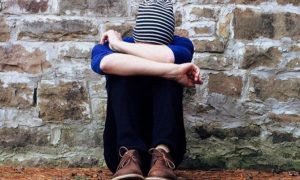 woman sits alone face on knees feeling upset sad depressed
