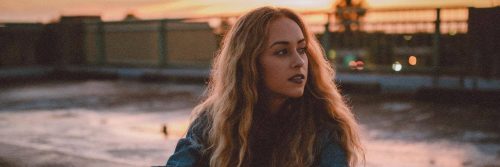 woman sits beside river looking aside in quiet peaceful environment