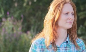 woman stands on field happily smiling during uncertain times