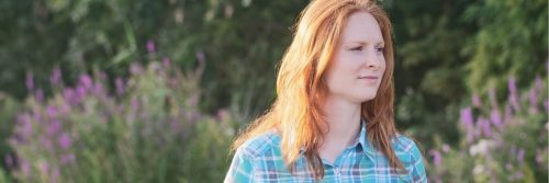 woman stands on field happily smiling during uncertain times