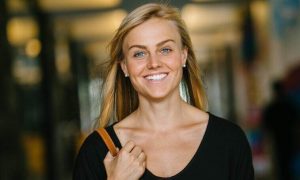 woman carrying back bag happily walks smiling