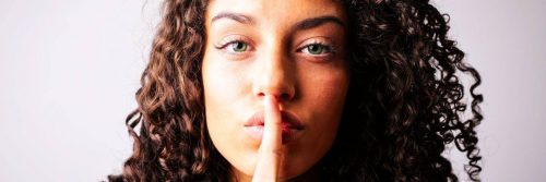 curly hair woman shows silence symbol