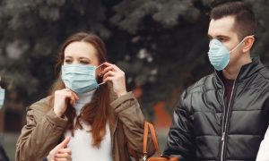 group of mixed genders wearing face masks standing on street talking