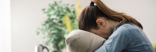 woman covers face with pillow crying