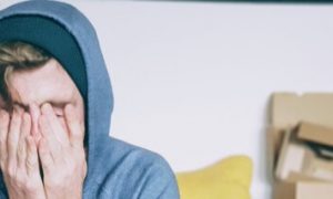 man sits hands in face feeling stressed tired
