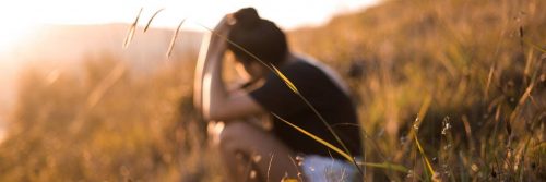 man sadly sits on field thinking