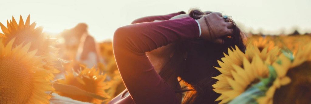 woman stands in sunflower field touching hair gratitude life in sunny sky