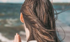 woman facing backward looks at ocean