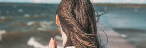 woman facing backward looks at ocean