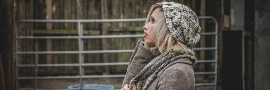 woman with worrying face stands beside fence
