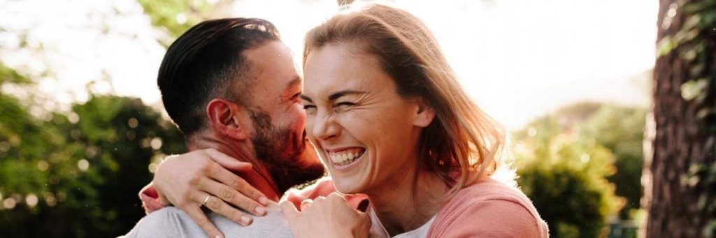 couple happily hugs in park in sunny sky