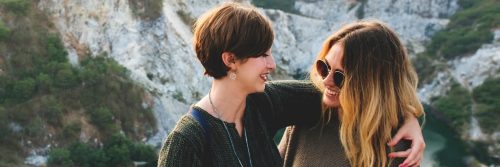 mom hugging daughter smiling talking beside mountain