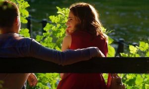couple sits on bench happily smiling beside lake