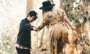 woman helping young man walk in forest