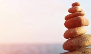 balanced stone rocks facing blue ocean in sunny sky