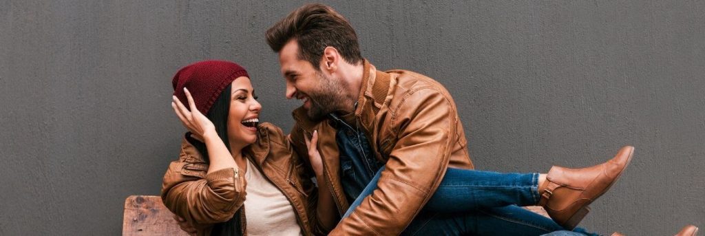 couple sits on bench happily talking laughing