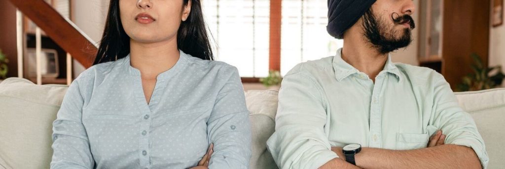 couple sits on white couch in living room not talking to each other