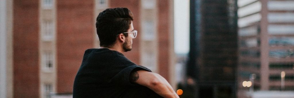 man sitting alone in city thinking